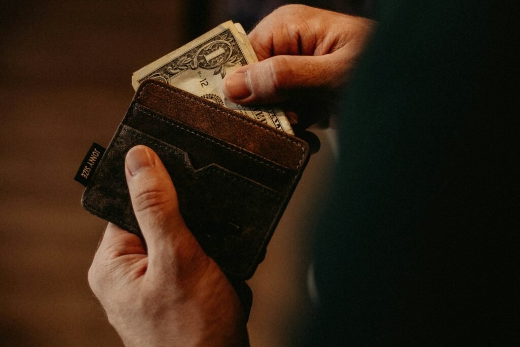 Person placing a one dollar banknote into a wallet