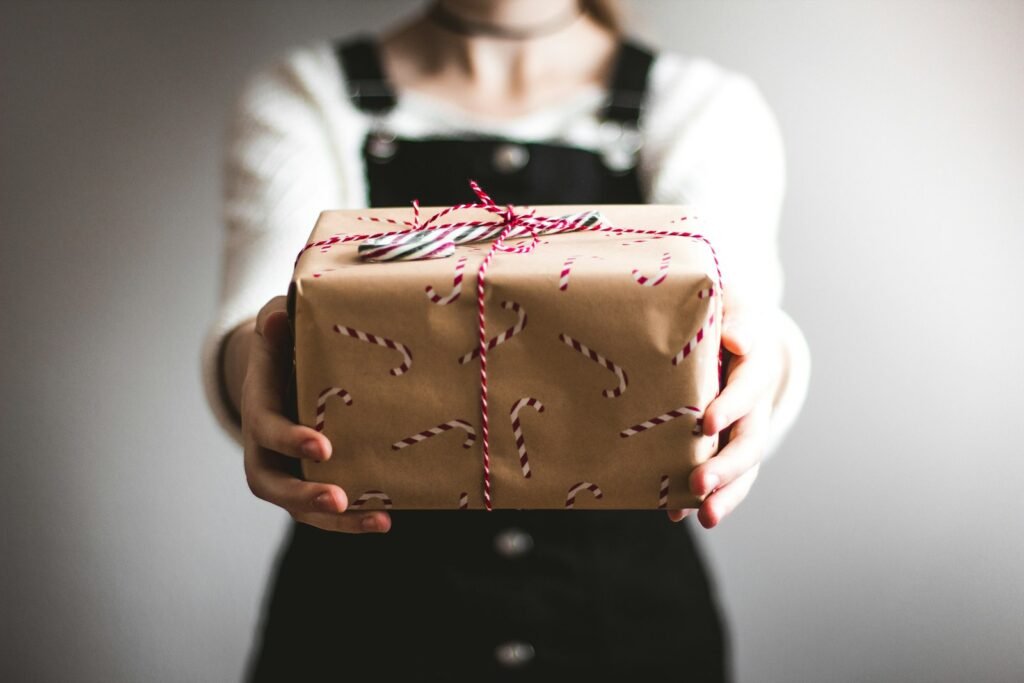 Person showing a brown gift box, presenting it as a gift