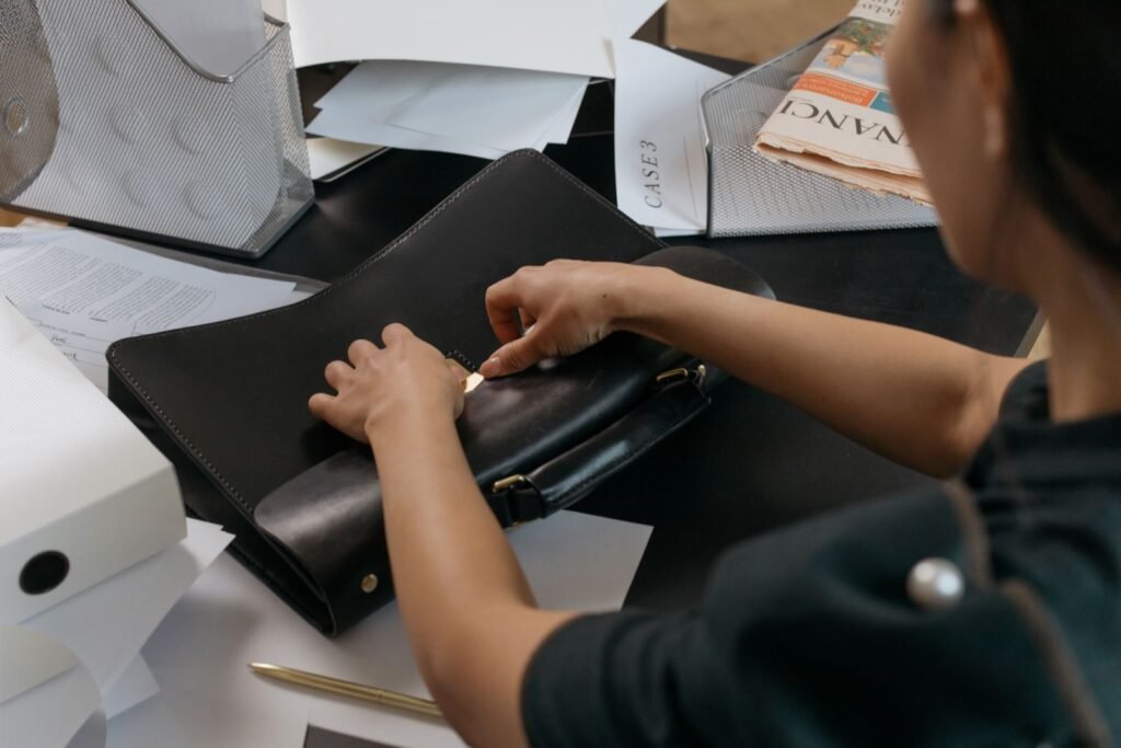 A professional organizing paperwork at an office desk with a leather briefcase