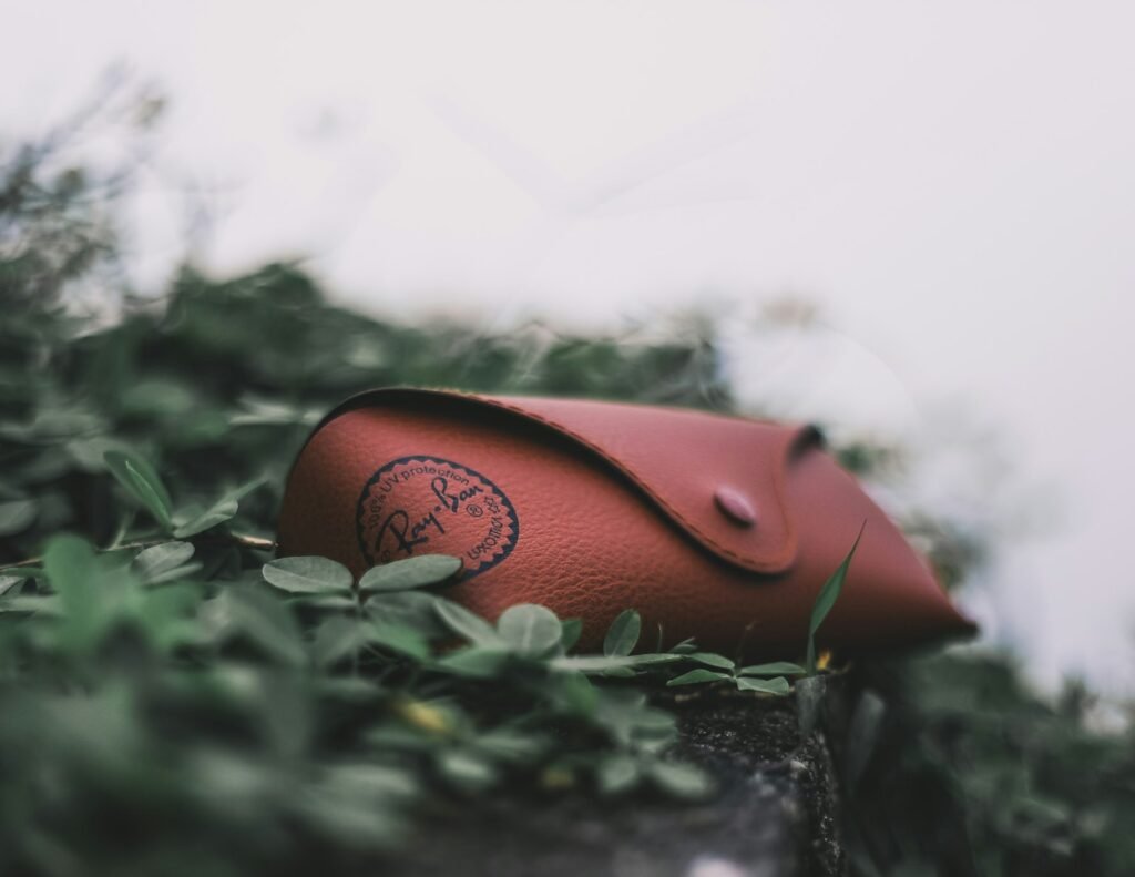 Red eyeglass case resting on leafy plants outdoors