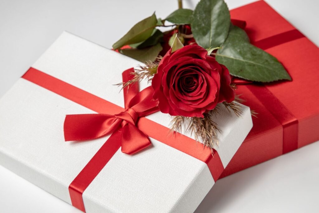 Close-up of a red rose atop elegantly wrapped gift boxes
