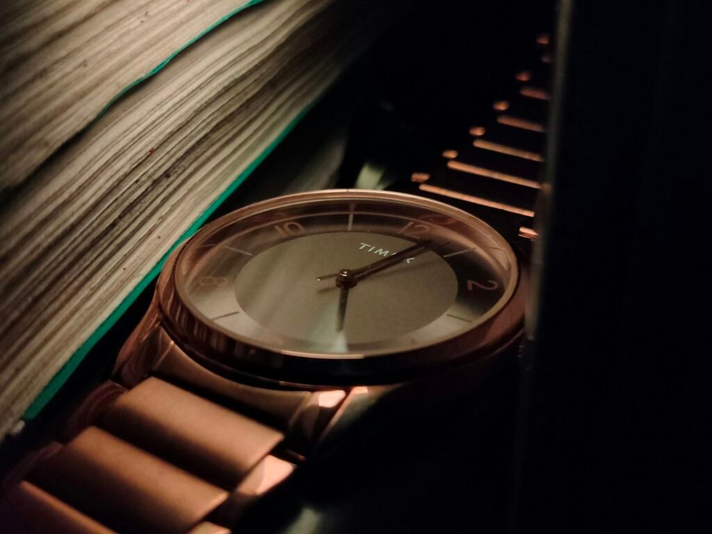 Close-up of a rose gold watch resting next to a stack of books