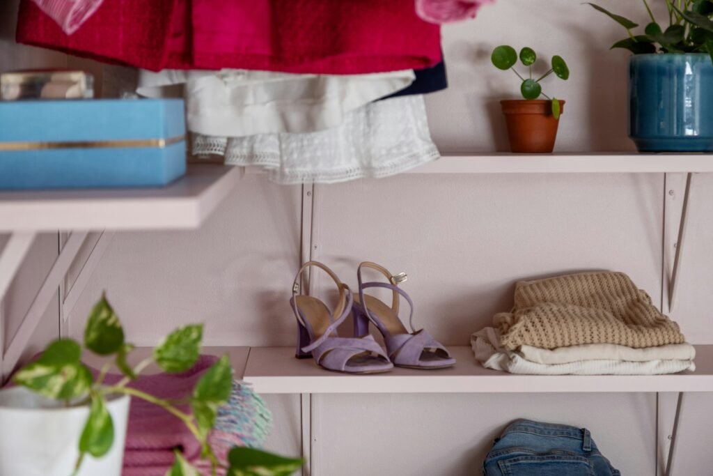 Shelf filled with clothes and shoes next to a potted plant