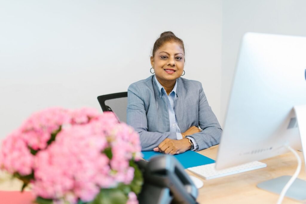 A smiling businesswoman sitting at her desk with flowers