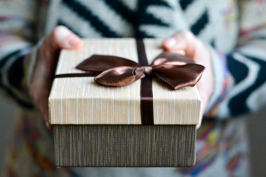Stylish gift box with brown ribbon held in hands