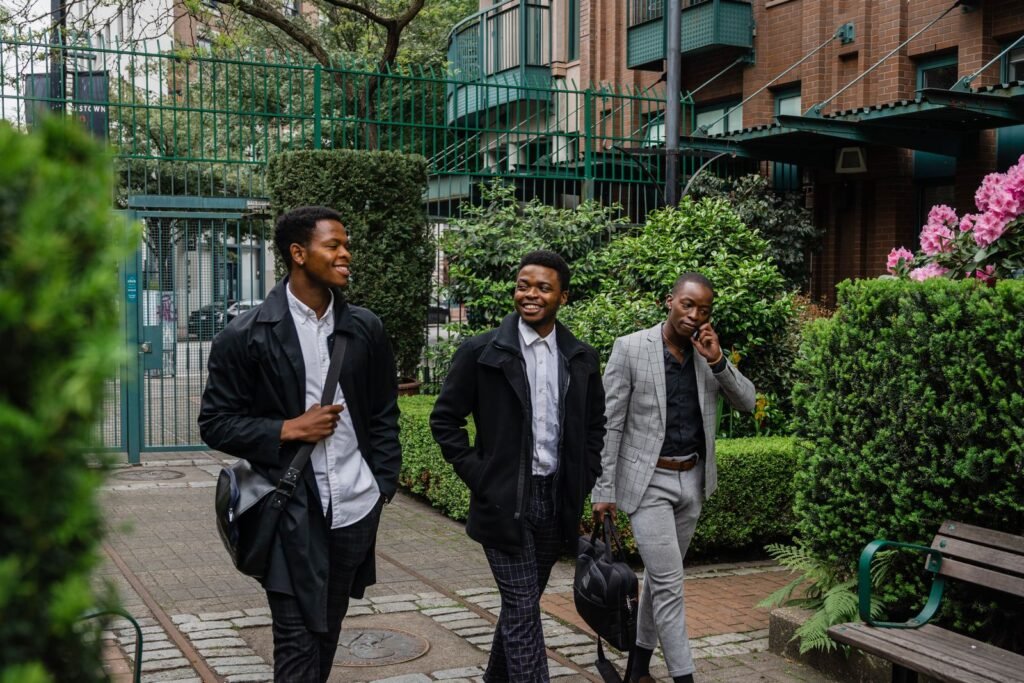 Three smiling businessmen walking outdoors in a garden area