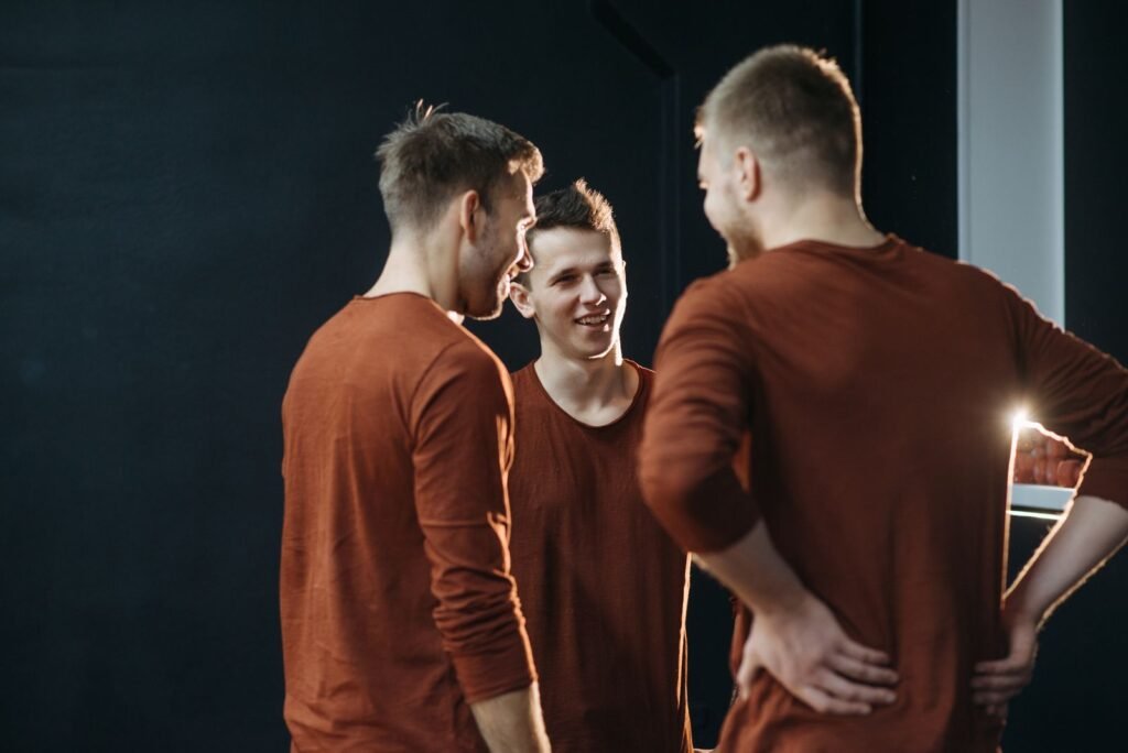 Three young men in casual brown attire share a light-hearted moment