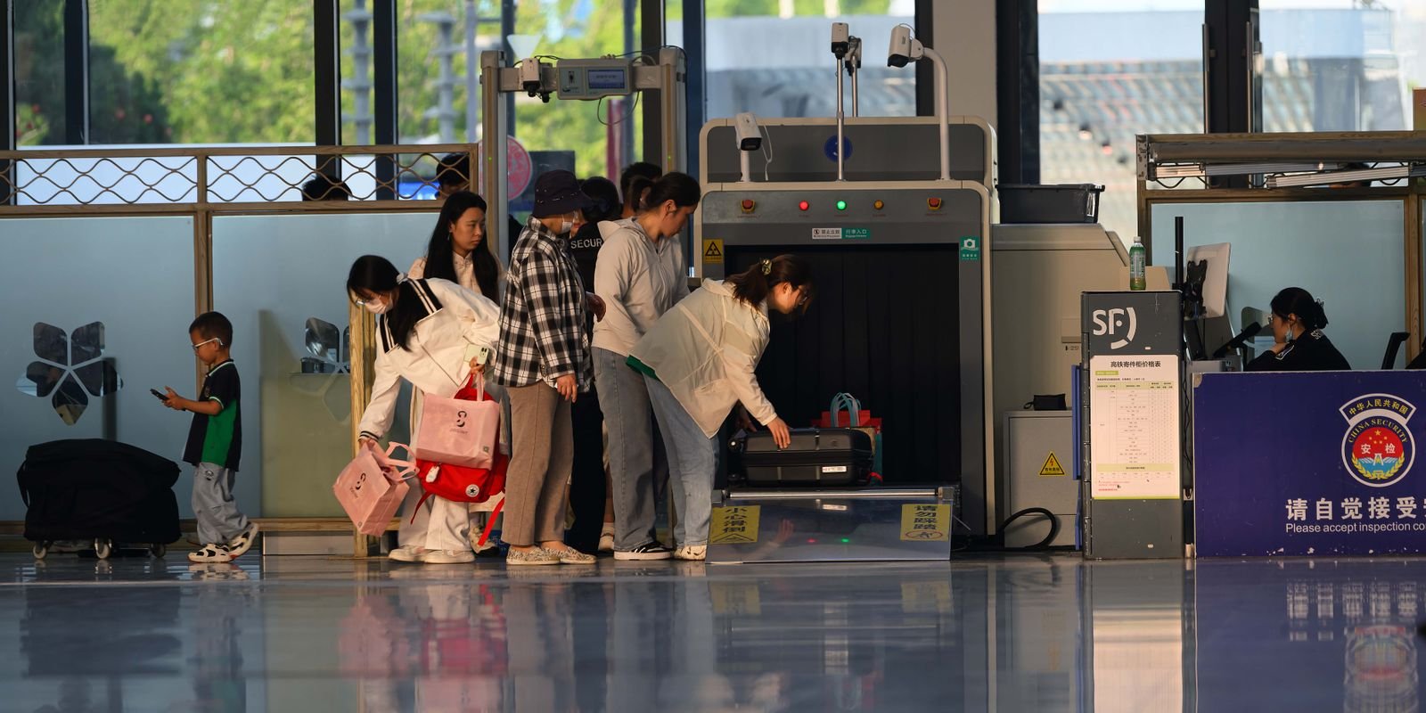 Travelers undergo security screening at an airport terminal