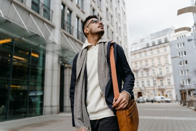 Trendy man with a leather bag standing confidently in an urban environment