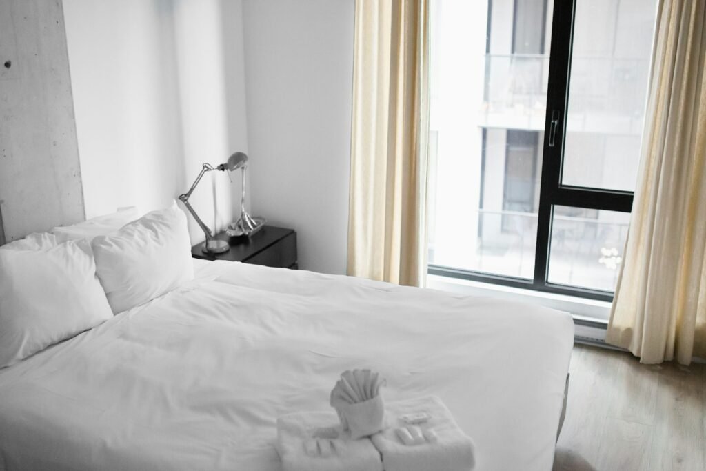 Vacant white bed near a window in a minimalist hotel room