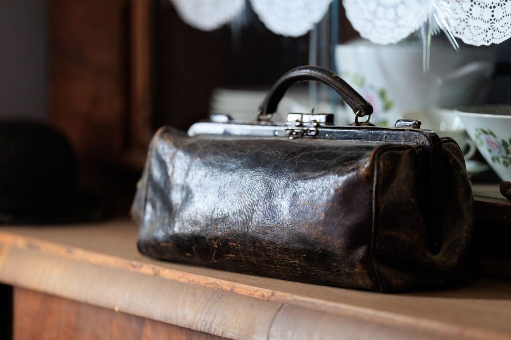 Close-up of a vintage leather bag resting on a wooden shelf