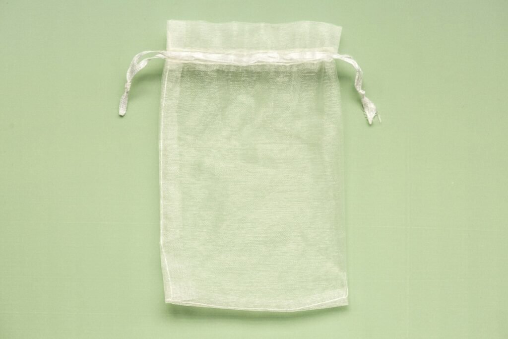 White cotton bag with a drawstring tied around it, similar to a dust bag