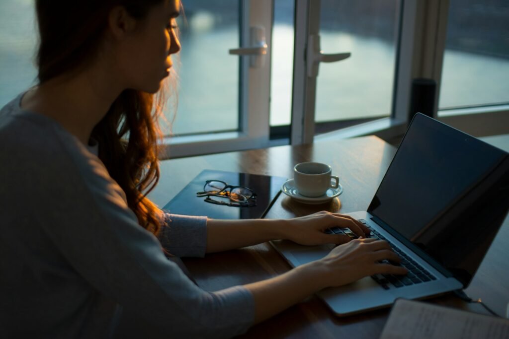 Woman sitting at a table using a laptop in a cafe setting