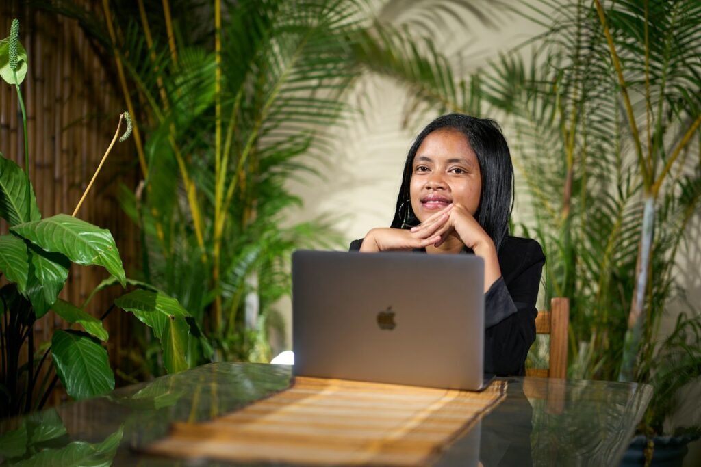 Young woman working on a laptop surrounded by plants in a tropical coworking space