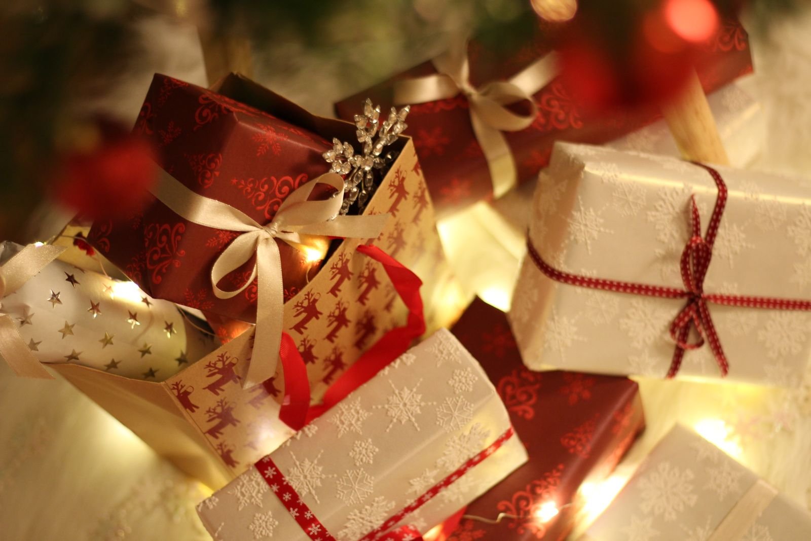 Beautifully wrapped Christmas presents under the tree with fairy lights